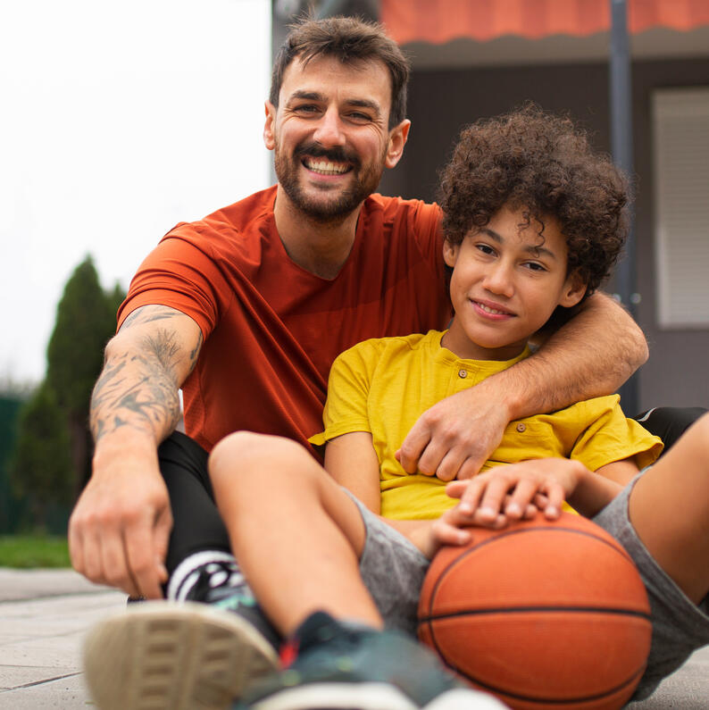 Padre e hijo con balón de baloncesto: comunicación positiva para padres de jóvenes deportistas.